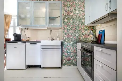 a kitchen with white appliances and floral wallpaper at Jugend 1903 in Ålesund