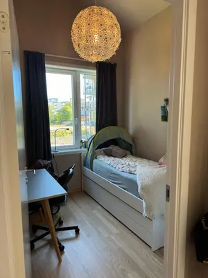 a small bedroom with a bed and a window at Modern 4 bedroom townhouse with garden and indoor car park in Trondheim