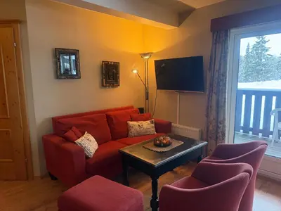 a living room with a red couch and a table at Charming Ground-Floor Apartment In Beitostølen With Terrace in Beitostøl