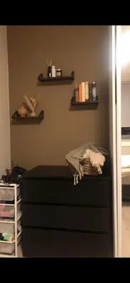 a bedroom with a dresser and shelves on the wall at Fin leilighet nært alt in Bergen