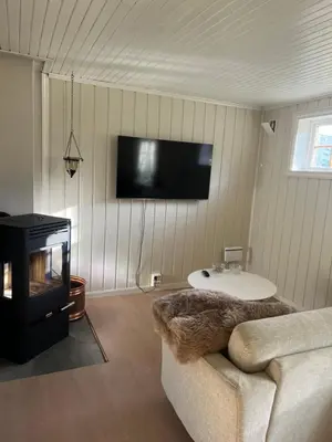 a living room with a couch and a tv on the wall at Haukedalen mountain panorama river view in Holsen