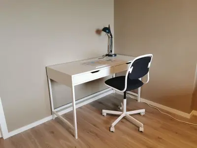 a white desk with a chair and a lamp at New and fresh apartment, free parking and ocean view in Trondheim