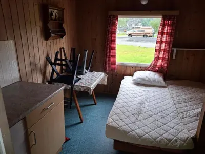 a room with a bed and a table and a window at Kvanndal Camping in Kvanndal