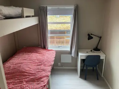 a bedroom with a bed and a desk and a window at Voss Resort self-catered apartments in Skulestadmo