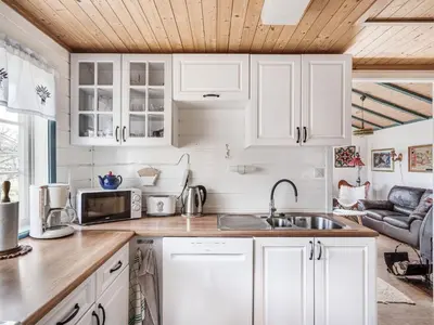a kitchen with white cabinets and a sink and a couch at Holiday Home Sandviki by Interhome in Balestrand