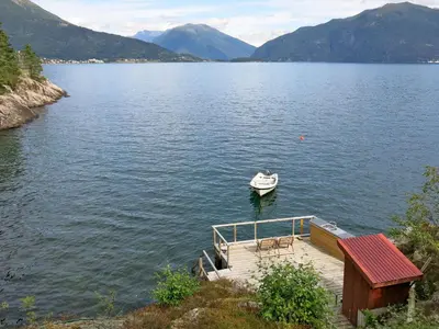 a small boat on a lake with a dock at Holiday Home Sandviki by Interhome in Balestrand