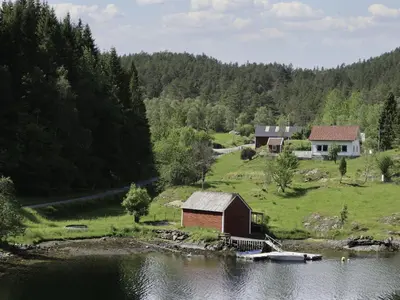 a house on a hill next to a body of water at Holiday Home Nystølen by Interhome in Håvik