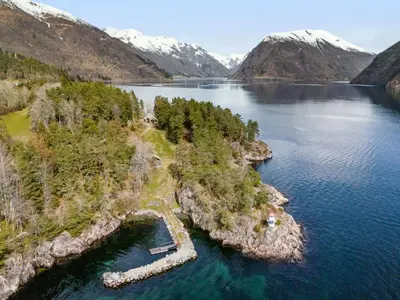 an island in the middle of a lake with mountains at Holiday Home Veganeset II by Interhome in Balestrand