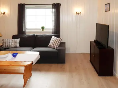 a living room with a black couch and a tv at Holiday Home Blåsenberg by Interhome in Bø
