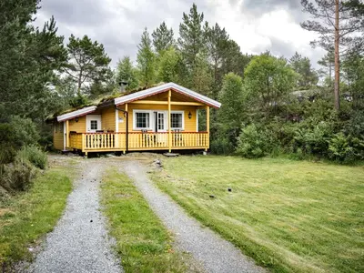 a small yellow house with a porch on a field at Holiday Home Solbakken by Interhome in Gjølanger