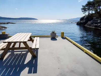 a picnic table sitting on a dock next to the water at Holiday Home Nesjevik by Interhome in Bø