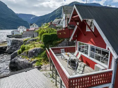 a red house with a deck next to a body of water at Holiday Home Balder by Interhome in Arnefjord
