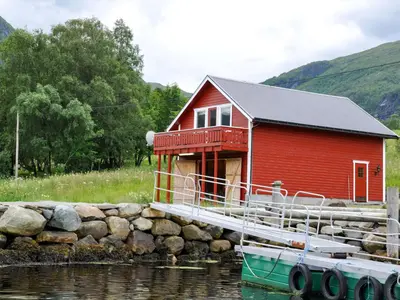 a red house on a dock with a boat in the water at Holiday Home Naustet by Interhome in Sylte