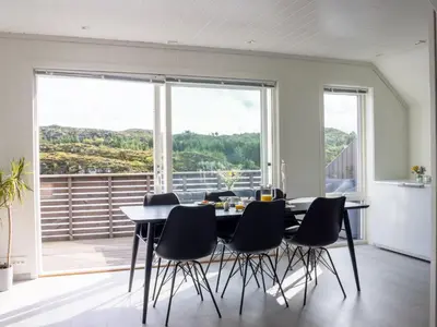 a dining room with a table and chairs and a large window at Holiday Home Torsk by Interhome in Bømlo