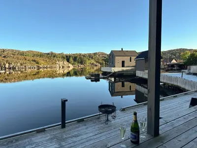 a bottle of wine sitting on a dock next to a lake at Holiday Home Lange by Interhome in Bømlo