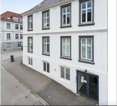 a white building with black windows on a street at Moderne leilighet midt i hjertet av Bergen Sentrum in Bergen