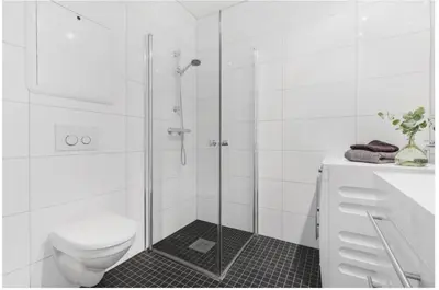 a white bathroom with a shower and a toilet at Moderne leilighet midt i hjertet av Bergen Sentrum in Bergen