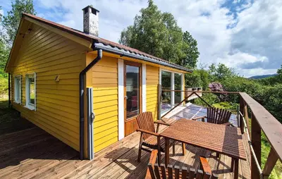 a small yellow house with a table and chairs on a deck at 1 Bedroom Stunning Home In Haugesund in Haugesund