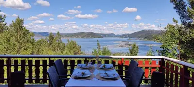a table on a balcony with a view of a river at Matthias Hytte in Fevåg