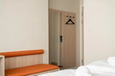 a bedroom with a closet and a bed with an orange bench at BREEZE Hotel Victoria - Self-Service in Bergen