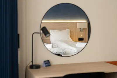 a mirror on a desk with a bed at BREEZE Hotel Victoria - Self-Service in Bergen