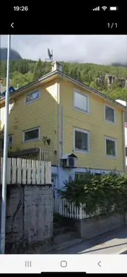 a yellow house with a fence in front of it at Gulthus in Odda