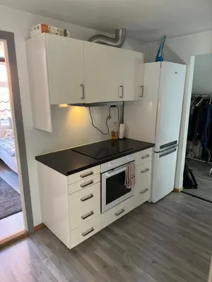 a kitchen with white cabinets and a black counter top at Spacious and central apartment I 250m from Bryggen in Bergen