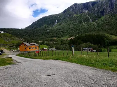 an empty road with a house and mountains in the background at Oynø in Etnesjøen