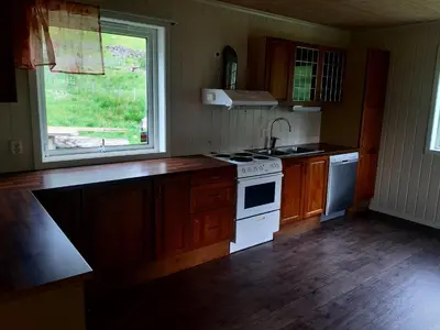 a kitchen with a stove and a sink and a window at Oynø in Etnesjøen