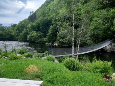 a bridge over a river next to a forest at Oynø in Etnesjøen