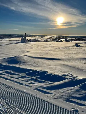 a field covered in snow with the sun in the background at Mountain appartment in Sjusjøen