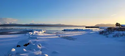 a river covered in snow with mountains in the background at Buviken Nordre, Femund in Sømådalen