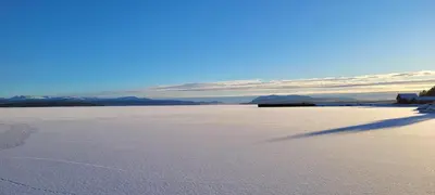 a shadow of a person walking across a snow covered field at Buviken Nordre, Femund in Sømådalen