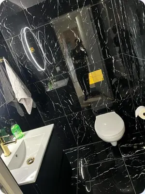 a black tiled bathroom with a toilet and a sink at Moderne Leilighet in Stord