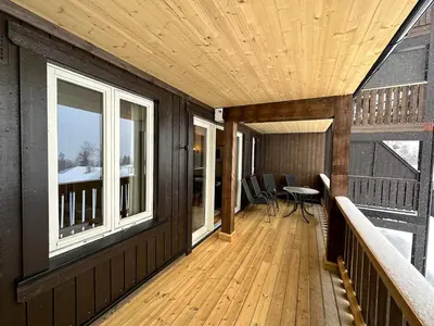 a wooden deck with a table and windows on a house at Family-Friendly Apartment Steps From Everything in Beitostøl