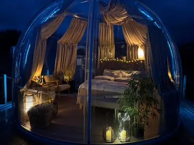 a bedroom with a bed in a glass dome at night at Atlantic Dome in Skotten