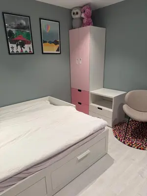 a bedroom with a bed and a cabinet and a chair at Villa med fantastisk uteplass! 10 sengeplasser! in Ålesund