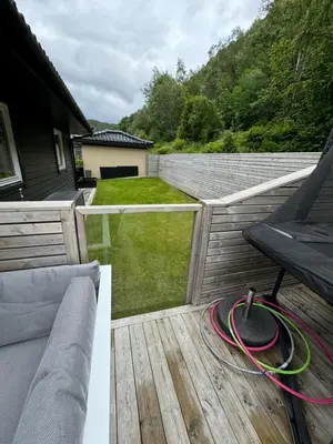 a patio with a hose on a wooden deck at Villa med fantastisk uteplass! 10 sengeplasser! in Ålesund