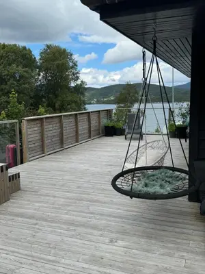 a swing on a deck with a view of the water at Villa med fantastisk uteplass! 10 sengeplasser! in Ålesund