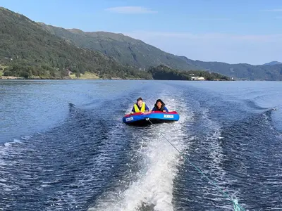 two people riding in a boat on a lake at Øen Hytter 1 in Sørbø