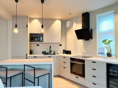 a kitchen with white cabinets and a counter with stools at Bergen City Apartment in Bergen