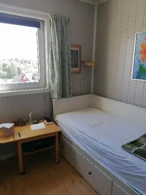 a bedroom with a bed and a table and a window at Leilighet nær Trondheim in Trondheim