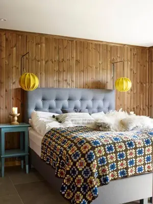 a bedroom with a bed with a blue headboard and two lights at Spacious Mountain Lodge Stryn in Stryn