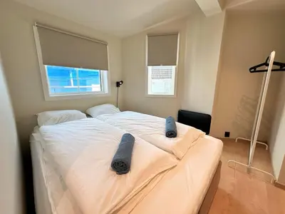 a bedroom with a white bed with two gray objects on it at Celestial Bergen Central Apartment in Bergen