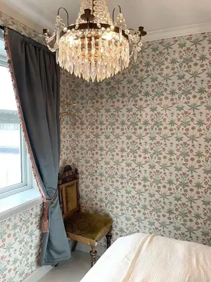 a chandelier in a bedroom with floral wallpaper at Jugend 1902 in Ålesund