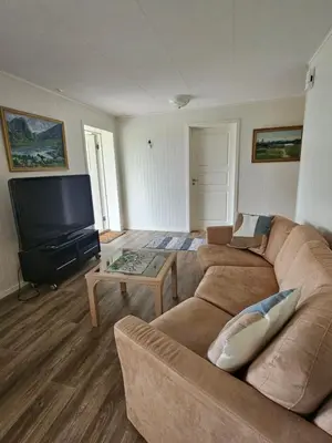 a living room with a couch and a flat screen tv at Gårdsidyll i flotte omgivelser in Ålesund