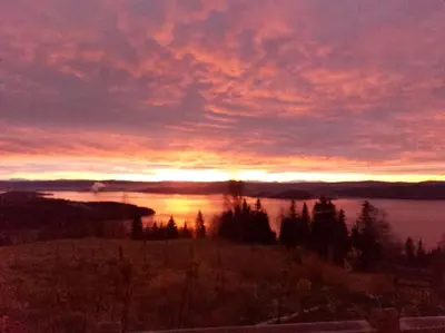 a sunset over a body of water with the sun setting at Guesthouse Hamran in Mosvik