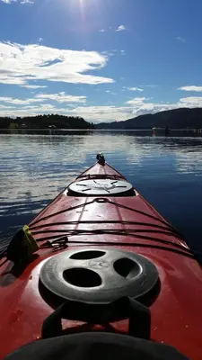 a red kayak sitting on a body of water at Åsenfjord, feriehus ved sjøen in Hopla
