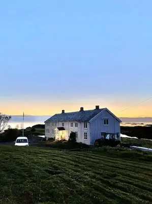 a white house sitting on top of a grass field at Sjønært småbruk in Bud