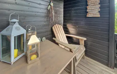 a wooden table with a lantern and a chair on a porch at Koselig Fjellhytte Med Utsikt in Bykle